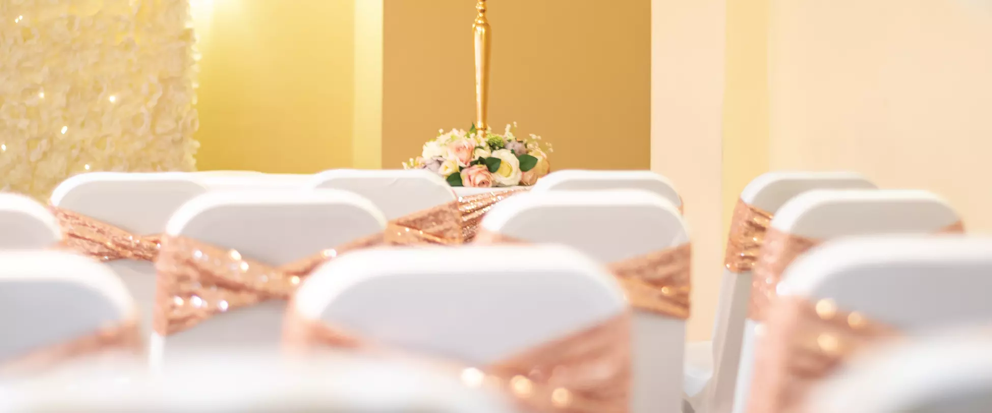 Chairs set up for a wedding with coverings and peach ribbons..