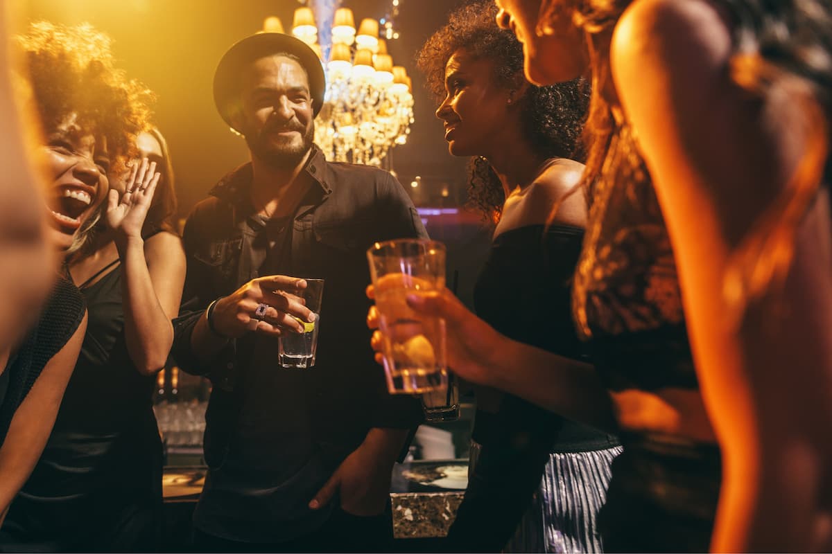 A group of men and women stood in a circle chatting at a party..